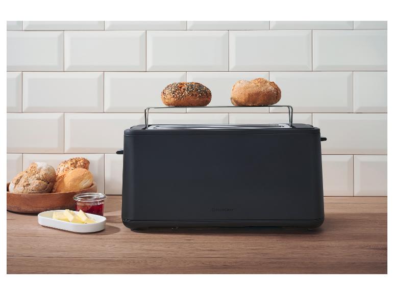 Grille-pain noir avec support à petits pains, beurre et confiture sur un comptoir en bois.