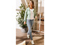 Une femme porte une veste en jean vert clair, un jean bleu et des baskets blanches.