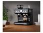 Machine à expresso noire avec moulin à café, préparant du café dans une tasse en verre sur une table en bois.