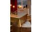 Table de salle à manger festive avec nappe dorée, bougies rouges et décorations de Noël.