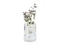 Vase en verre cannelé avec de l'eucalyptus et des fleurs violettes.