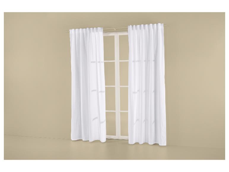 Voilages blancs sur une tringle à rideaux, devant une fenêtre aux cadres blancs.