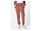 Une femme porte un pantalon de survêtement en velours rose et des baskets blanches.