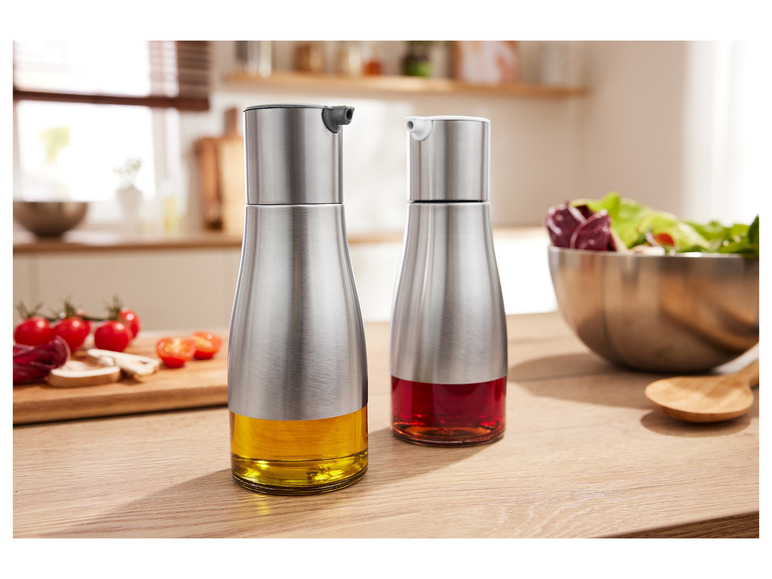 Deux flacons d'huile en acier avec de l'huile et du vinaigre sur une table en bois