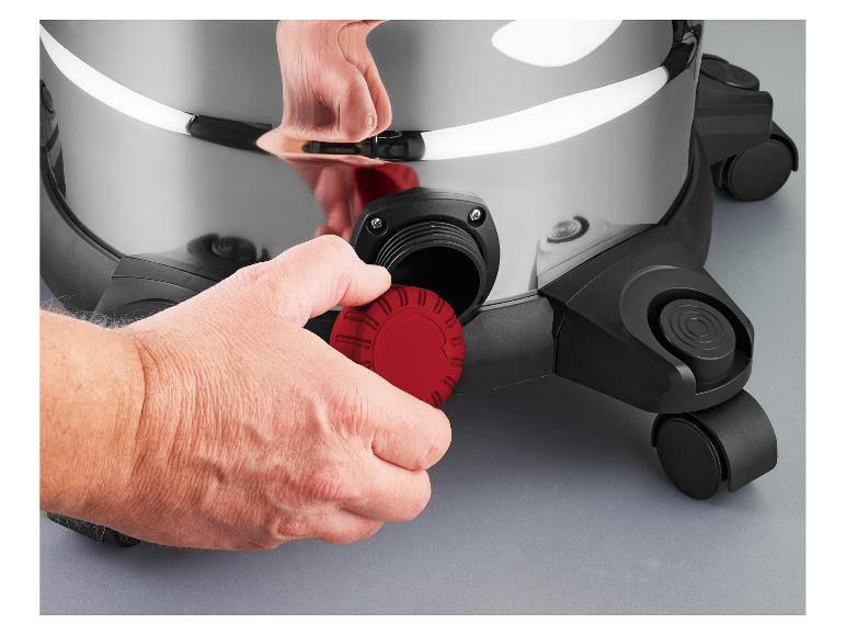 Main vissant un bouchon rouge sur un aspirateur argenté.