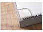 Matelas gris avec mousse sur un sol en bois.