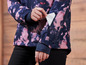Une femme portant une veste rose et bleue avec un imprimé tie-dye, avec une poche sur la manche.
