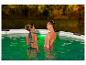 Deux femmes en maillots de bain dans une piscine illuminée.