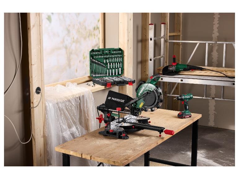 Scie à onglet, meuleuse d'angle et perceuse sur un établi avec un jeu de douilles dans un atelier.