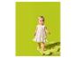 Bébé en robe rayée colorée, debout sur une couverture verte