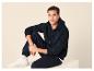 Homme en sweat à capuche et pantalon de survêtement bleu foncé, assis avec des baskets blanches.