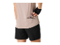 Femme en haut de sport et short, prenant une barre énergétique de la poche arrière.