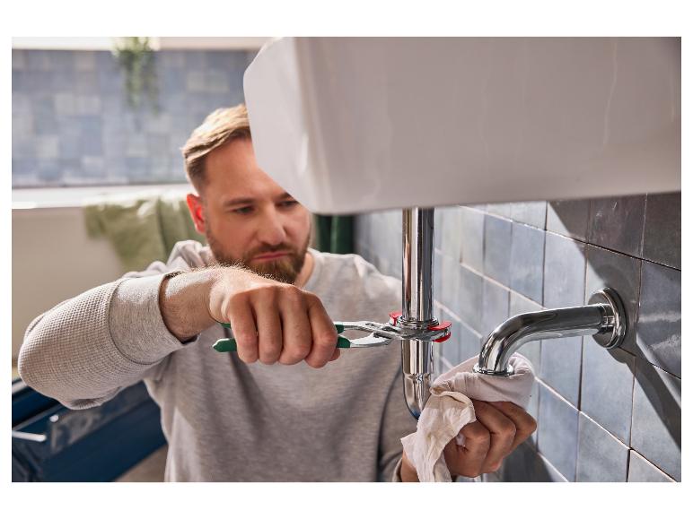 Un homme répare le siphon d'un lavabo avec une pince.