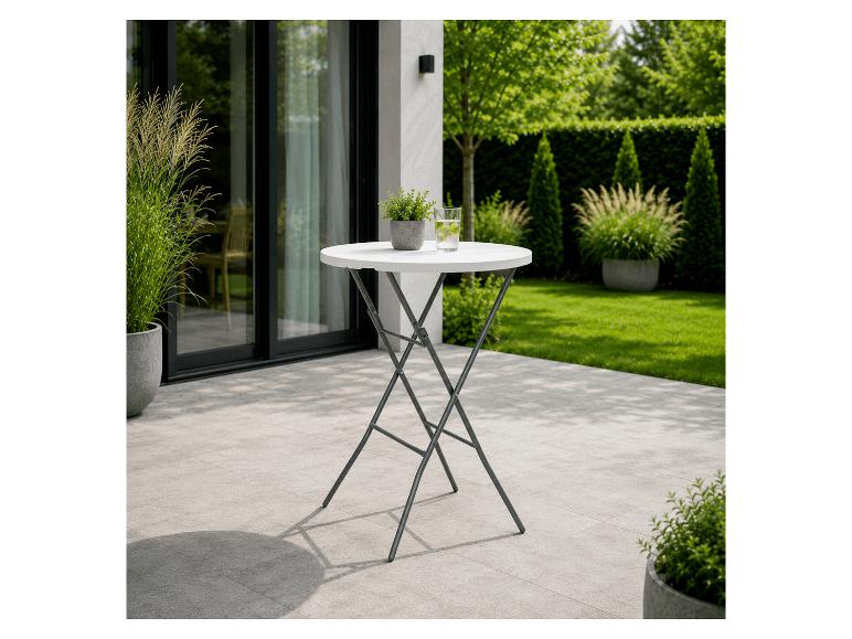 Table de bistrot blanche avec plante et verre d'eau sur une terrasse avec jardin.