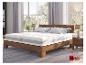 Lit en bois avec deux matelas blancs et oreillers dans une chambre lumineuse avec fenêtre.