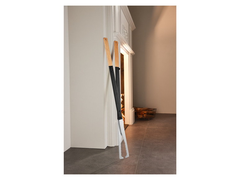 Deux outils de cheminée en bois, une pince et une pelle, sont posés devant une cheminée.