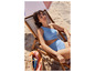 Une femme en bikini bleu sur une chaise longue de plage avec un panier en osier.
