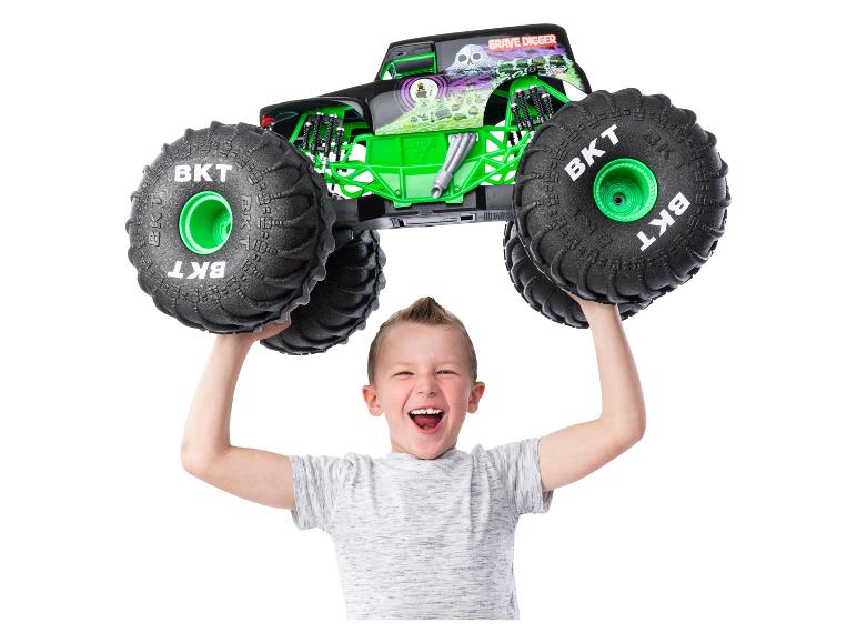 Un garçon tenant un jouet camion monstre Grave Digger Monster Jam au-dessus de sa tête.