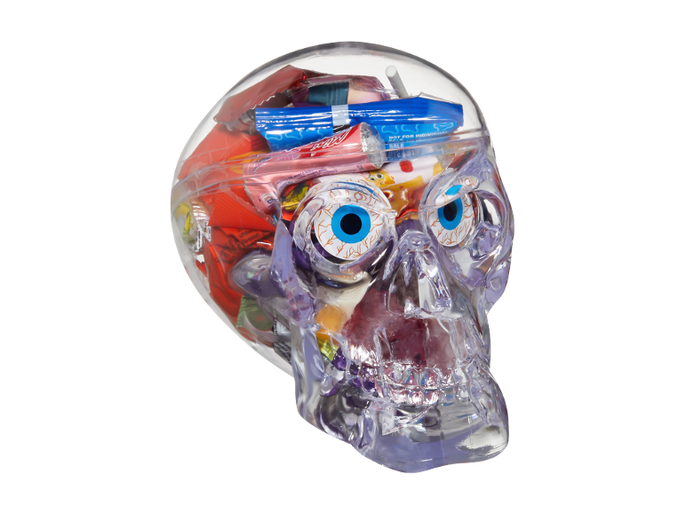 Crâne transparent rempli de bonbons d'Halloween assortis, y compris des yeux en gélatine et des friandises emballées.