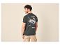 Homme de dos en T-shirt vert foncé avec imprimé montagne et short beige.