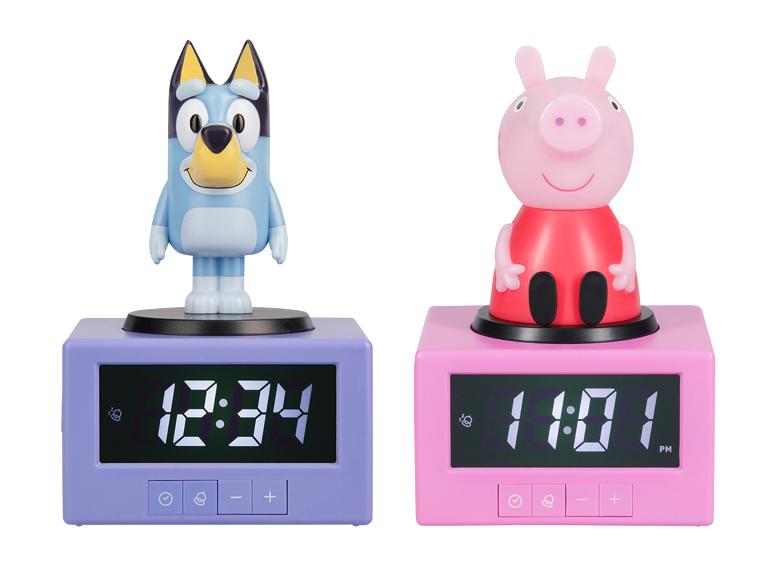 Deux réveils à l'effigie de personnages, un chien bleu et un cochon rose, affichant des heures différentes.