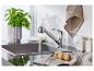 Robinet de cuisine chromé, évier en acier inoxydable et accessoires.