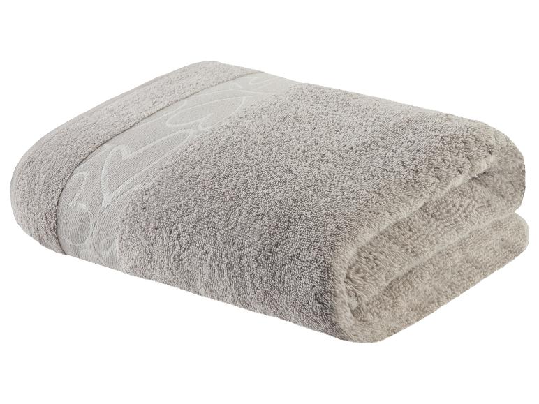 Une serviette grise pliée avec un motif brodé.