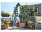 Une femme arrose des plantes en pots sur un balcon.