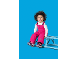 Jeune enfant en combinaison de neige rose et bottes, assis sur une luge bleue.