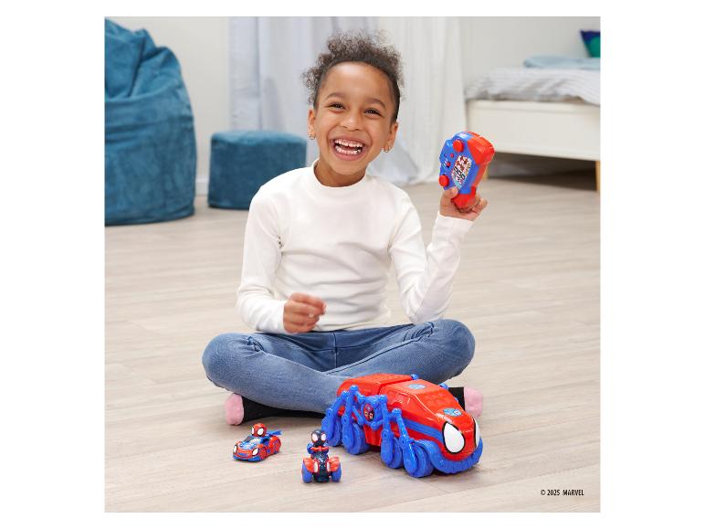 Un enfant joue avec des véhicules jouets sur le thème de Spider-Man et une télécommande.