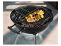 Un barbecue noir avec une grille et un plat à cuire, sur lequel sont cuits des saucisses et des pommes de terre.