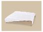 Couette blanche matelassée sur un lit en bois avec fond beige.