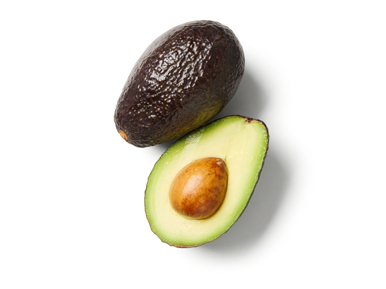 Avocat entier et avocat coupé en deux avec noyau sur fond blanc.