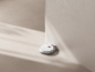Aspirateur robot blanc sur sa station de charge contre un mur beige