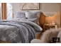 Chambre chaleureuse avec parure de lit grise à flocons de neige et plaid en maille.