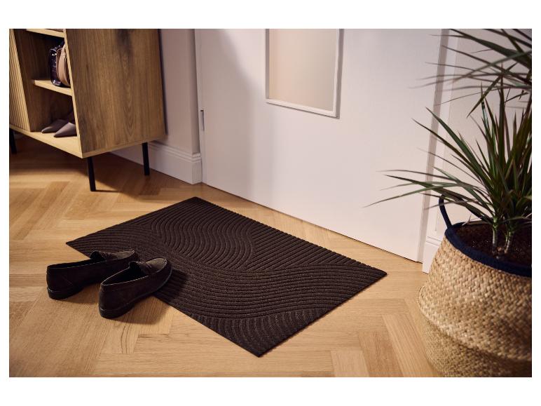 Paillasson LIVARNO® marron avec motif ondulé près de la porte.