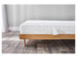 Un matelas blanc sur un sommier en bois sur un sol en bois.