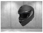 Un casque de moto noir avec visière sur un fond en béton.