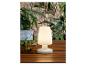 Une lampe blanche avec une base ronde sur une table en bois.