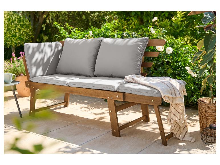 Banc de jardin en bois avec coussins gris sur une terrasse verdoyante