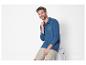 Un homme porte un polo bleu Sea Voyage et un short beige.