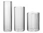 Trois vases en verre cylindriques avec des cannelures verticales.