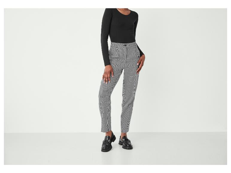 Une femme porte un haut noir et un pantalon à carreaux.