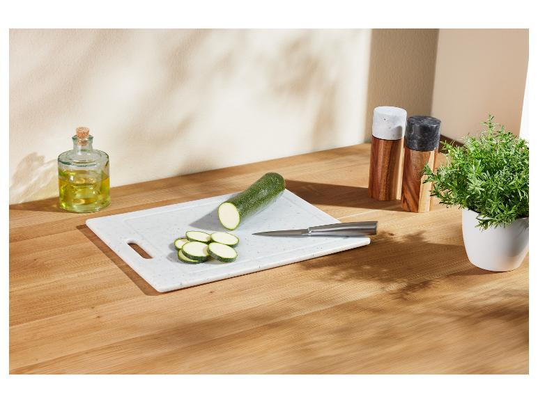 Courgettes coupées sur une planche à découper, avec de l'huile d'olive et des herbes.