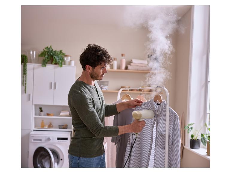 Un homme défroisse une chemise avec un défroisseur à main dans une buanderie.