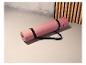 Un tapis de yoga rose Crivit avec une sangle noire.