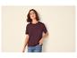 Femme en t-shirt bordeaux et jean, la main dans la poche.
