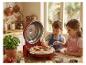 Deux enfants préparent une pizza avec un four à pizza rouge, ingrédients frais sur une table en bois.