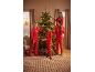 Une famille en pyjamas de Noël rouges assortis décore un sapin de Noël.