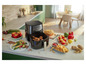 Une friteuse à air Philips avec du poulet rôti, des frites, des muffins et des légumes.